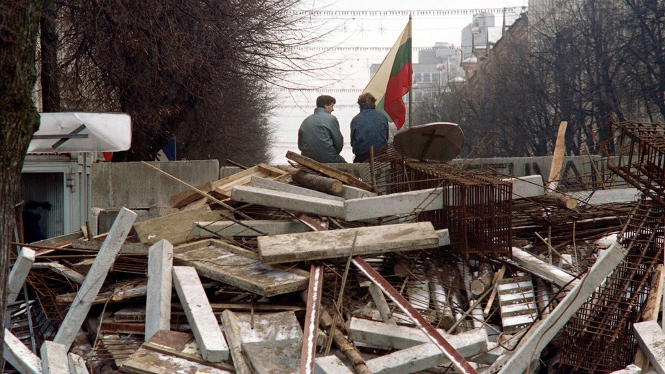 Photo of two men with a Lithuanian flag guarding a barricade