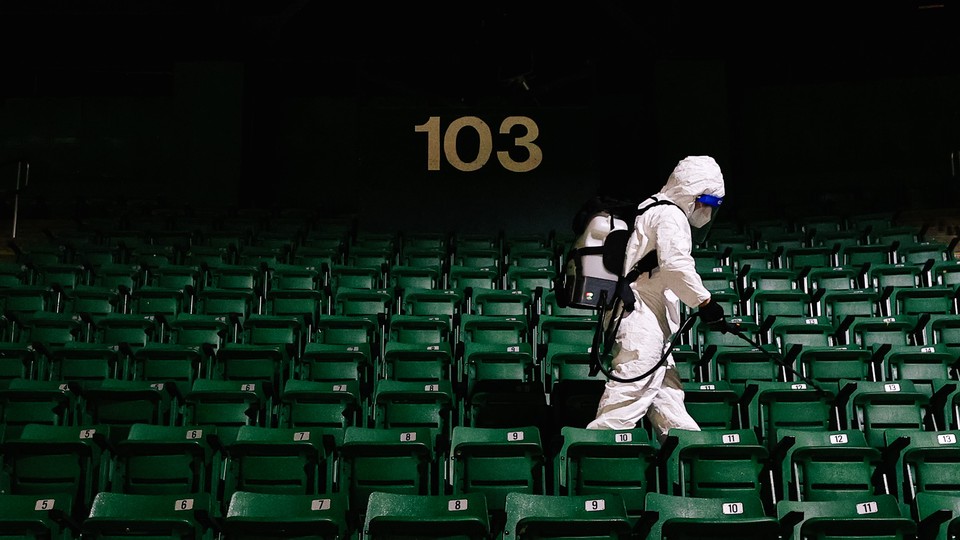 A worker disinfecting seats at a sports stadium