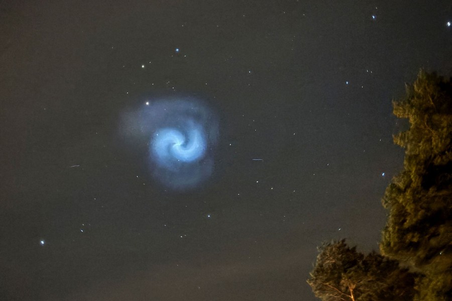 A blue and white spiral in the night sky, apparently from a failed rocket launch