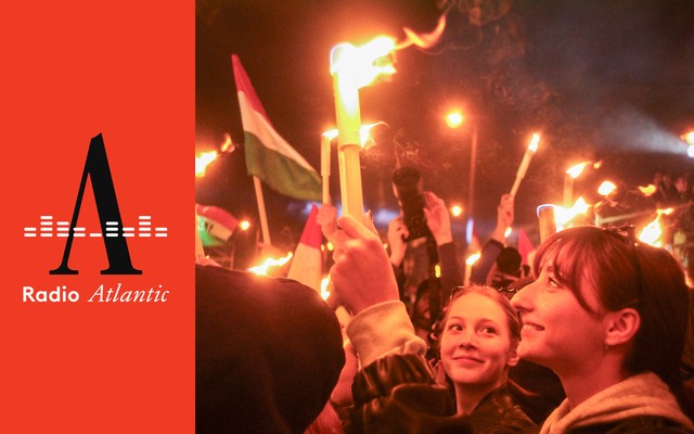 A crowd celebrates Hungarian-election results, waving flags and holding candles.