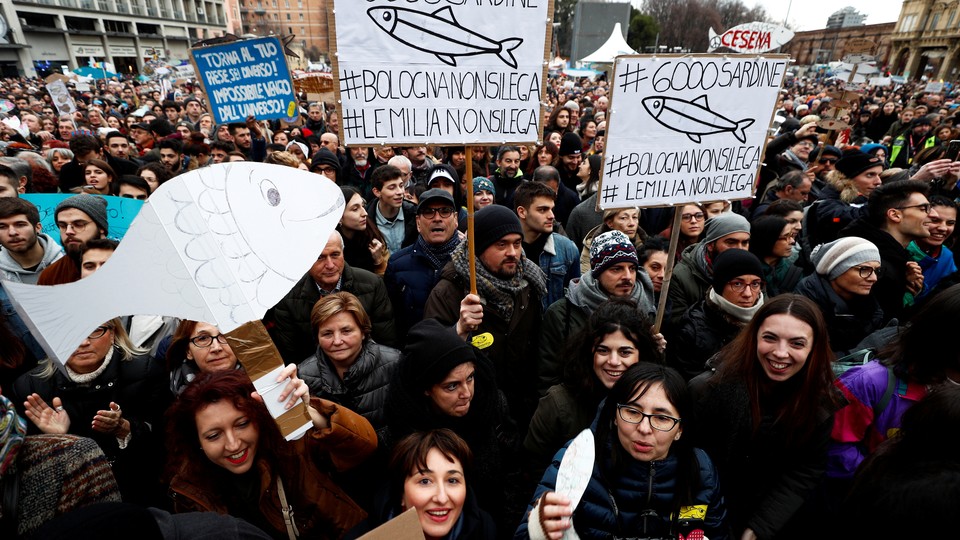 People with signs shaped like sardines gather in Italy.