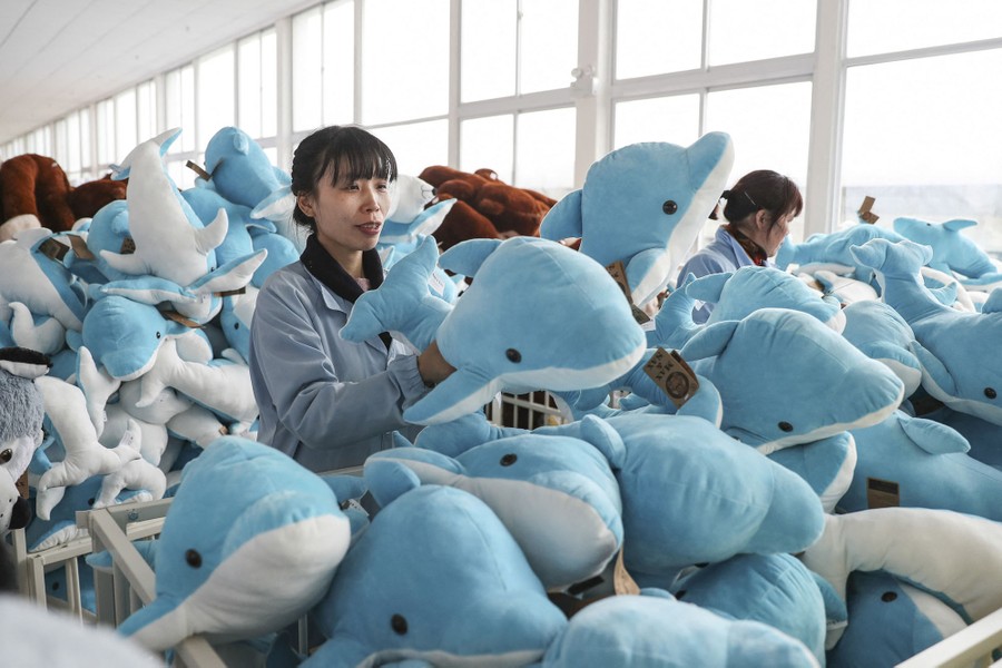 Workers check piles of stuffed dolphins.