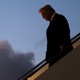 Color photograph of Trump walking down the stairs on Air Force One.