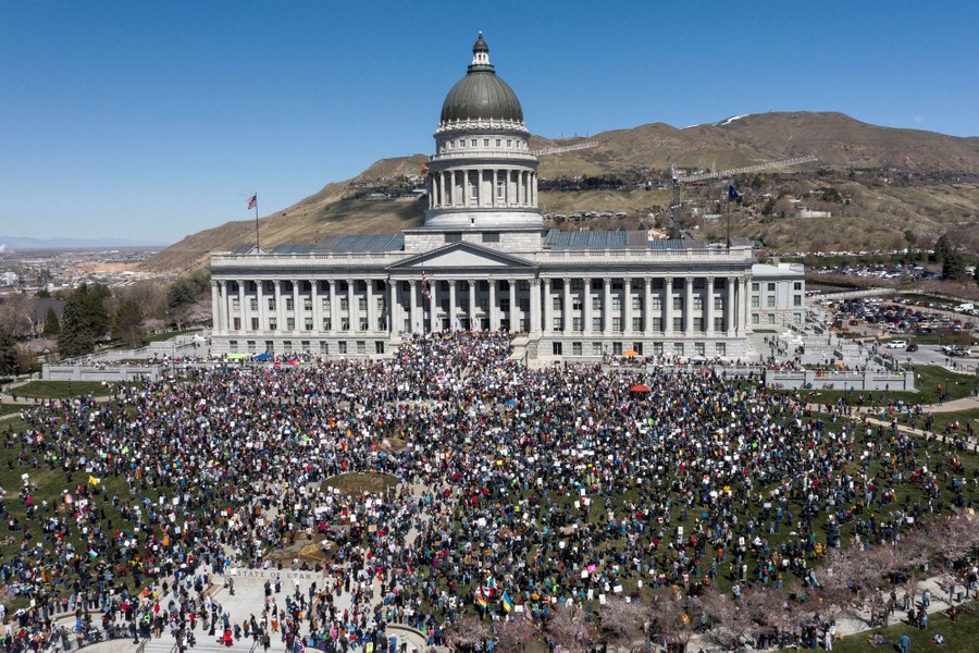 A large crowd of protesters gathers outside a state capitol building.