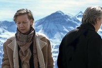 Sandra Hüller and Samuel Theis looking in opposite directions against a backdrop of snowy mountains