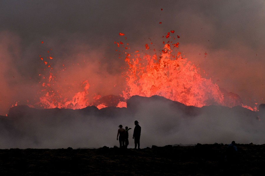 Several people watch flowing lava during an volcanic eruption.