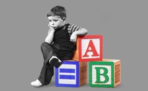 A kid pondering on a pile of ABC blocks.