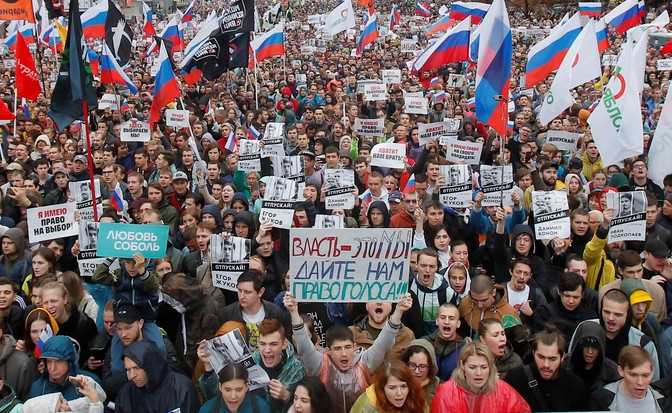 Protesters hold up placards and flags at a rally in Moscow.