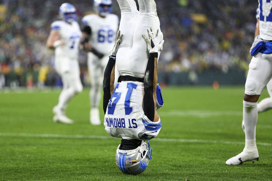 A football player stands on his head during a celebration at a game.