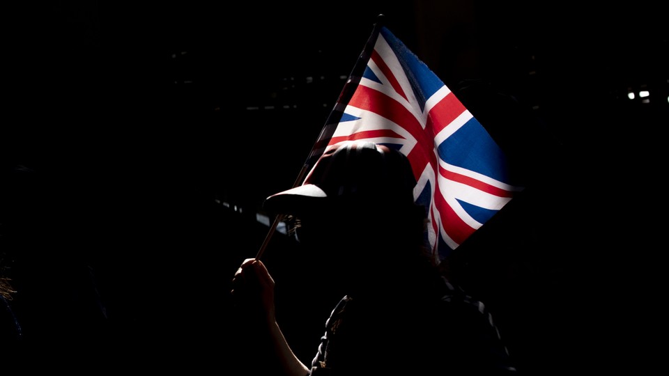 A silhouetted person holds up a Union Jack flag.