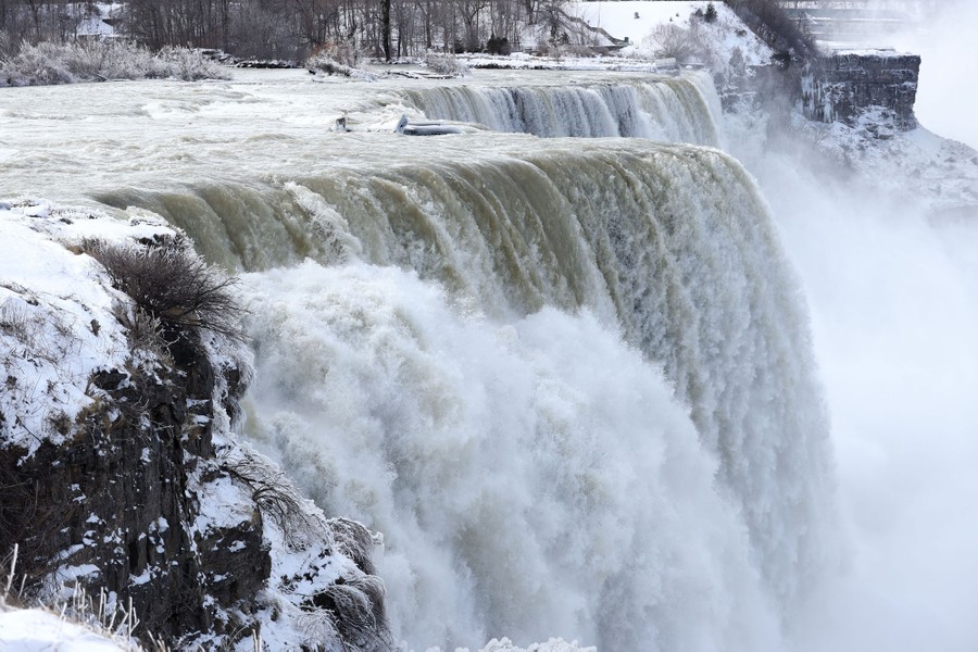 Water tumbles over Niagara Falls, flanked by snow and ice at the edges.