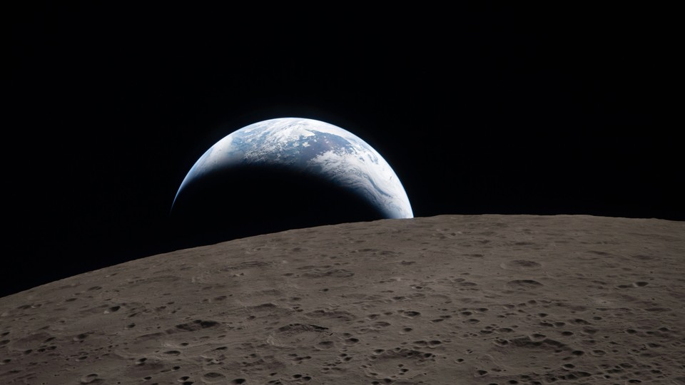 A photo of the Earth in a crescent shape, with the dark side of the moon in the foreground.