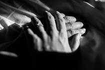A black-and-white photo of a woman's hand resting over a man's hand