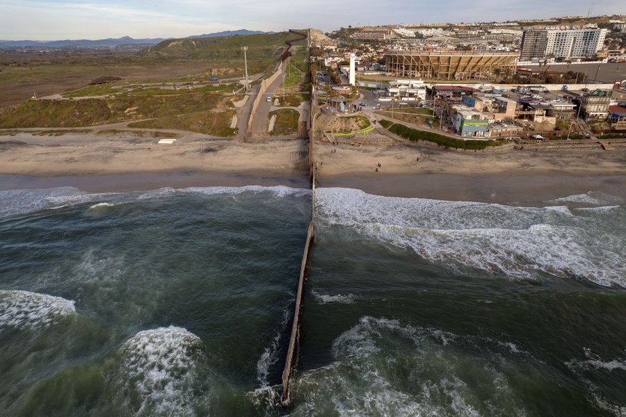 An aerial view of the U.S.-Mexico border wall at the Pacific shoreline.