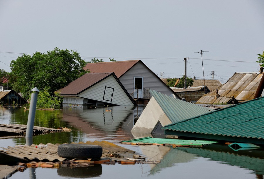 A flooded residential area, with houses and sheds knocked askew