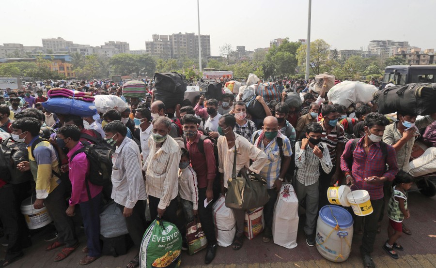 Many people crowd together in lines, awaiting transportation.