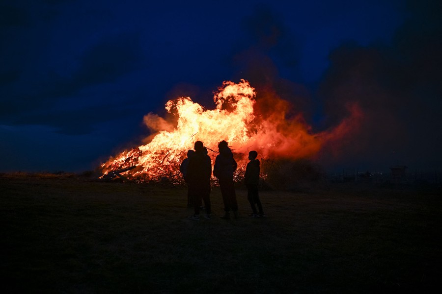 People watch a bonfire at night.