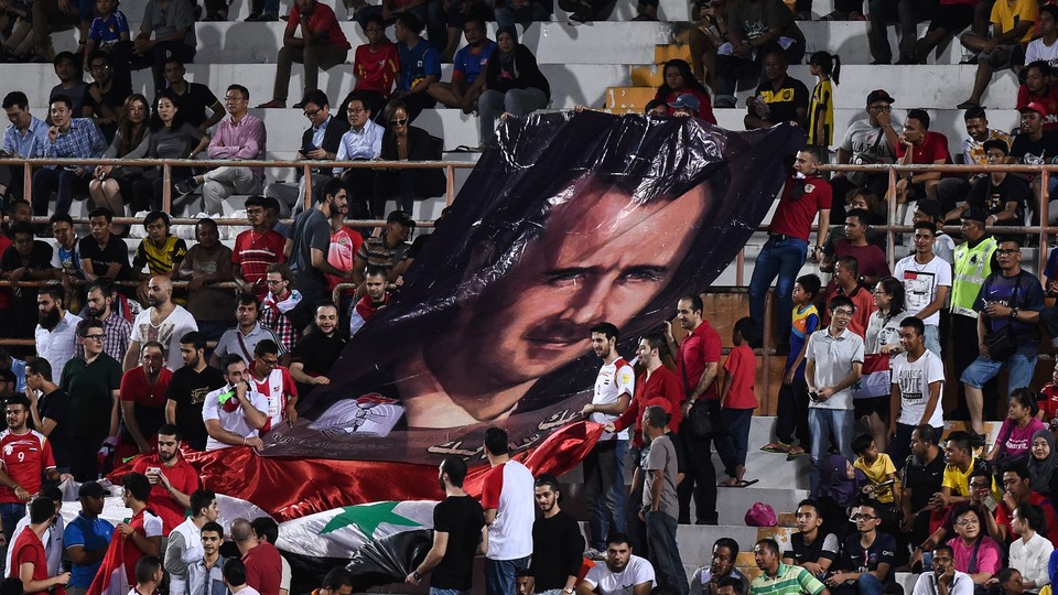 Syrian football supporters display a portrait of Syrian President Bashar al-Assad during the 2018 World Cup qualifying football match between South Korea and Syria.