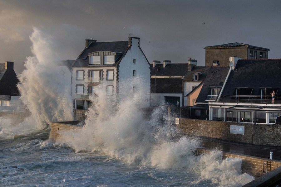 Waves hit the shore, crashing up alongside houses.