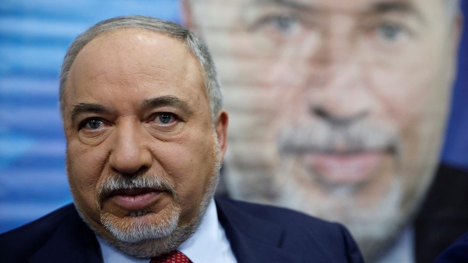 Avigdor Lieberman stands in front of a painted image of himself.