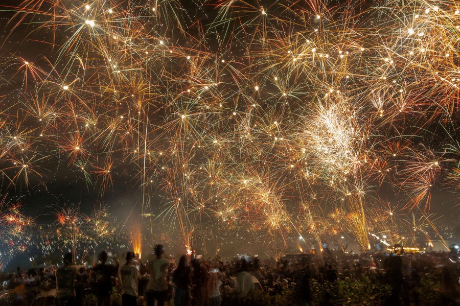 People look up at a sky filled with fireworks.