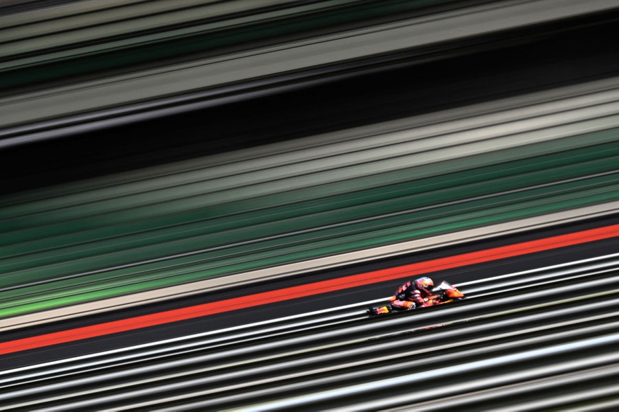 A motion-blurred image of a racing motorcyclist, making the bike appear stationary while the surrounding world is made of stripes.