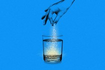 A hand sprinkling powder into a glass