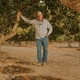 Matt Angell posing between almond tress on an orchard