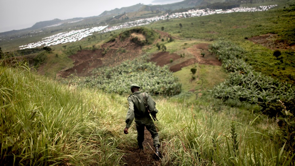 Photo of a Congolese soldier patrolling a hillside covered in vegetation