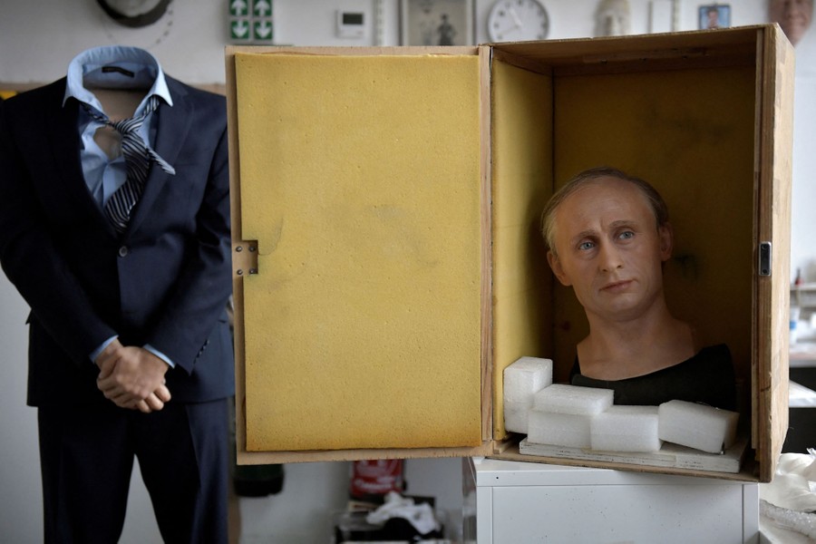 A headless statue stands to the left, while, to the right, an open wooden box can be seen with a wax head of Russian President Vladimir Putin inside.