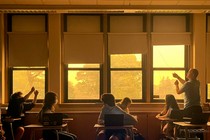 A teacher closes the shades of windows looking out on a haze of wildfire smoke.