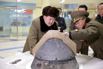 North Korean leader Kim Jong Un looks at a rocket warhead tip