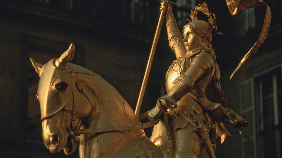 A golden statue of Joan of Arc looking defiant on her horse.