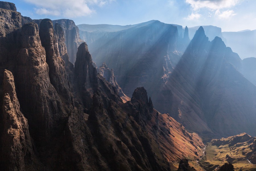 Sunlight filters through the atmosphere among steep rocky mountains.