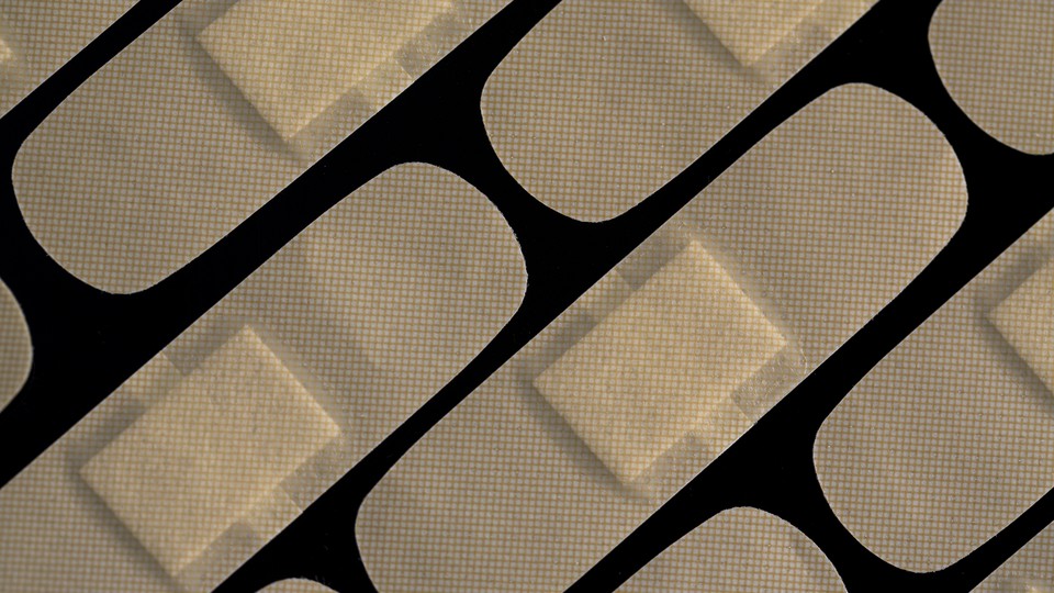 An array of tan Band-Aids on a black background