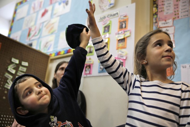 Elyse Dweck, 4, right, and Joey Arking, 5, raise their hands in their pre-kindergarten class at the Al & Sonny Gindi Barkai Yeshivah in Brooklyn, New York, Wednesday, March 11, 2015.