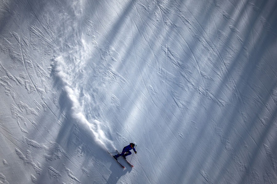 A skier is seen speeding down a steep slope.