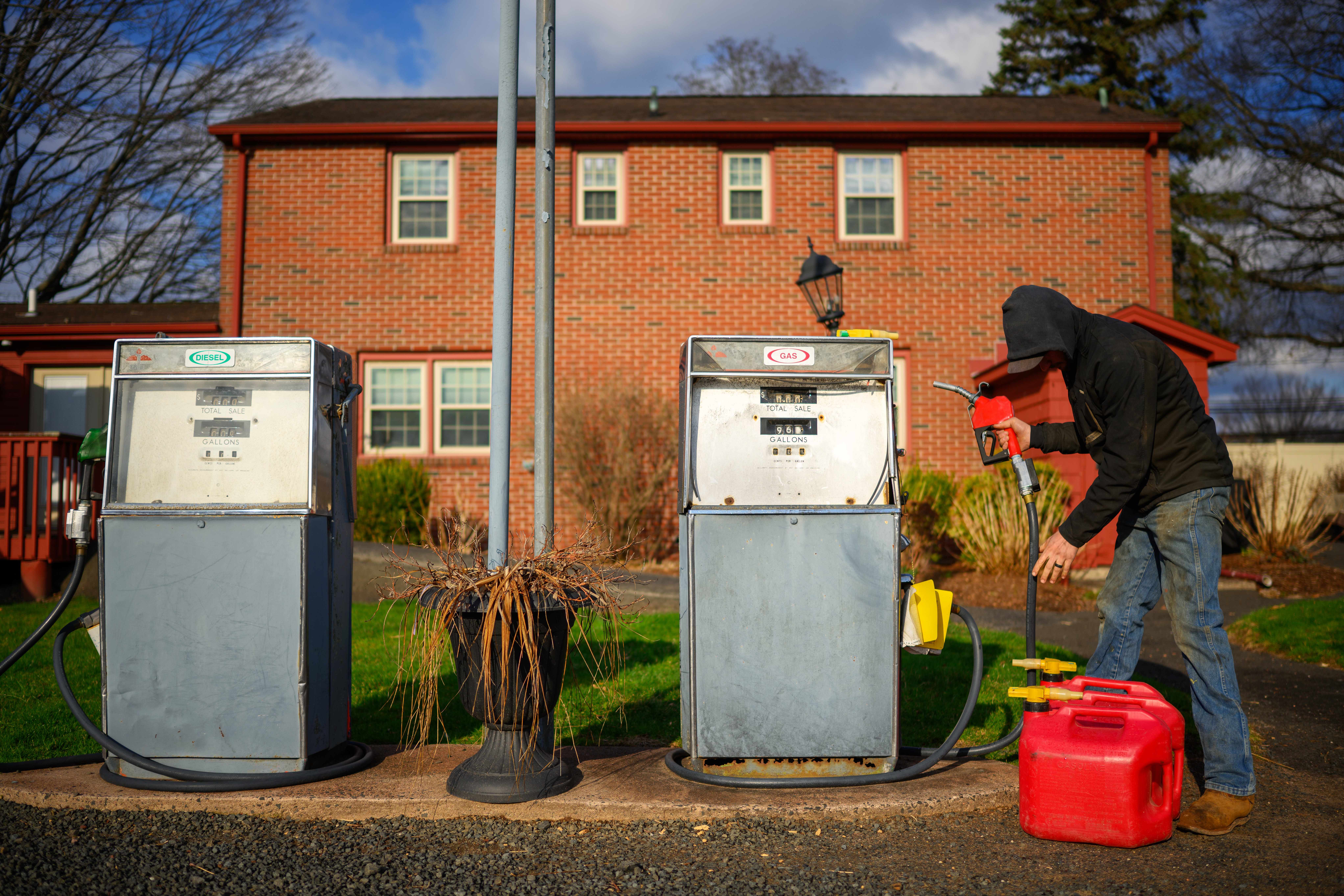 A person fills a container with fuel at one of two pumps on a farm.