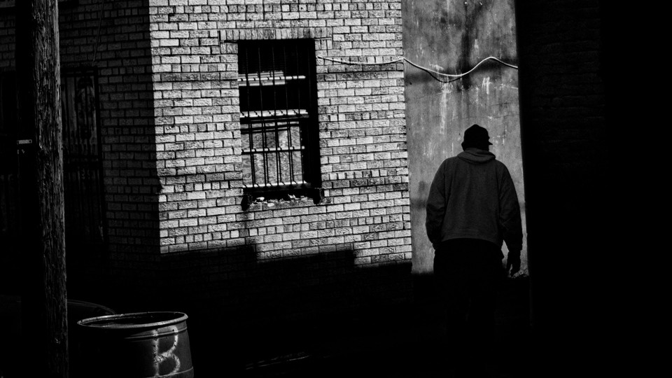 A shadowy figure walks through an alley