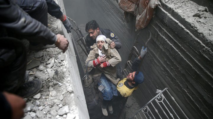 Syria Civil Defence members help an unconscious woman from a shelter in the besieged town of Douma, Eastern Ghouta, Damascus, on February 22, 2018.
