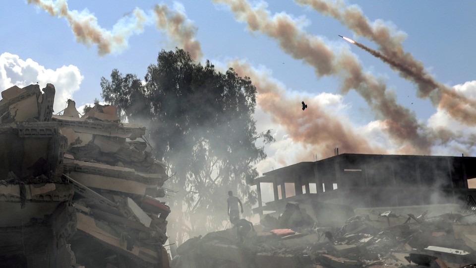 Rockets fired from the Gaza Strip over buildings destroyed by Israeli air strikes