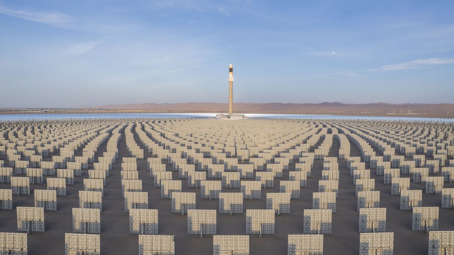 Thousands of evenly spaced solar mirrors surround a tall tower in a desert