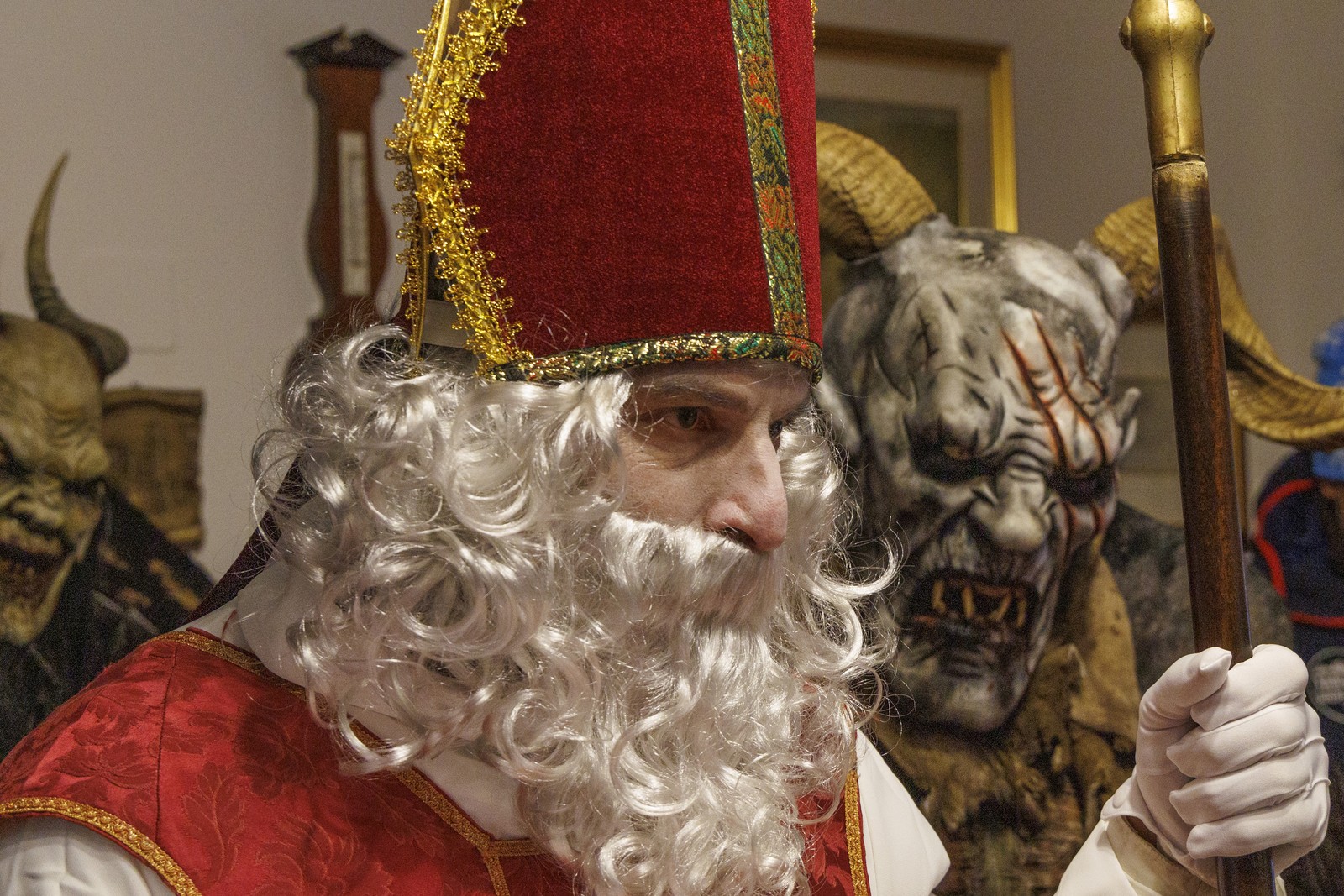 A person wearing a Saint Nicholas costume stands beside several costumed, demonic characters.
