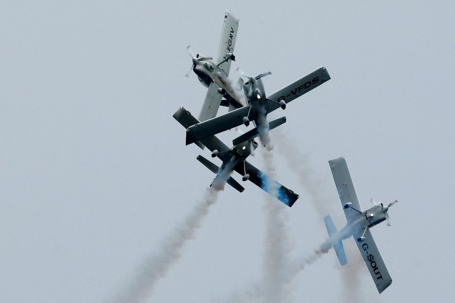 Four small planes fly very close together at varying angles, during an air show.