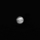 A gif of Jupiter and its stormy atmosphere in black and white, steadily growing larger