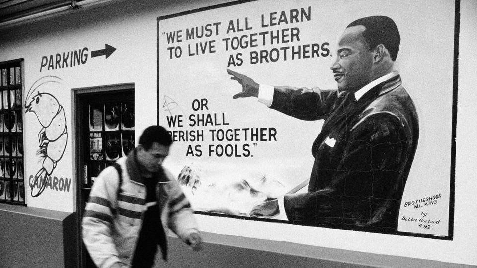 A man walking in front of an MLK mural