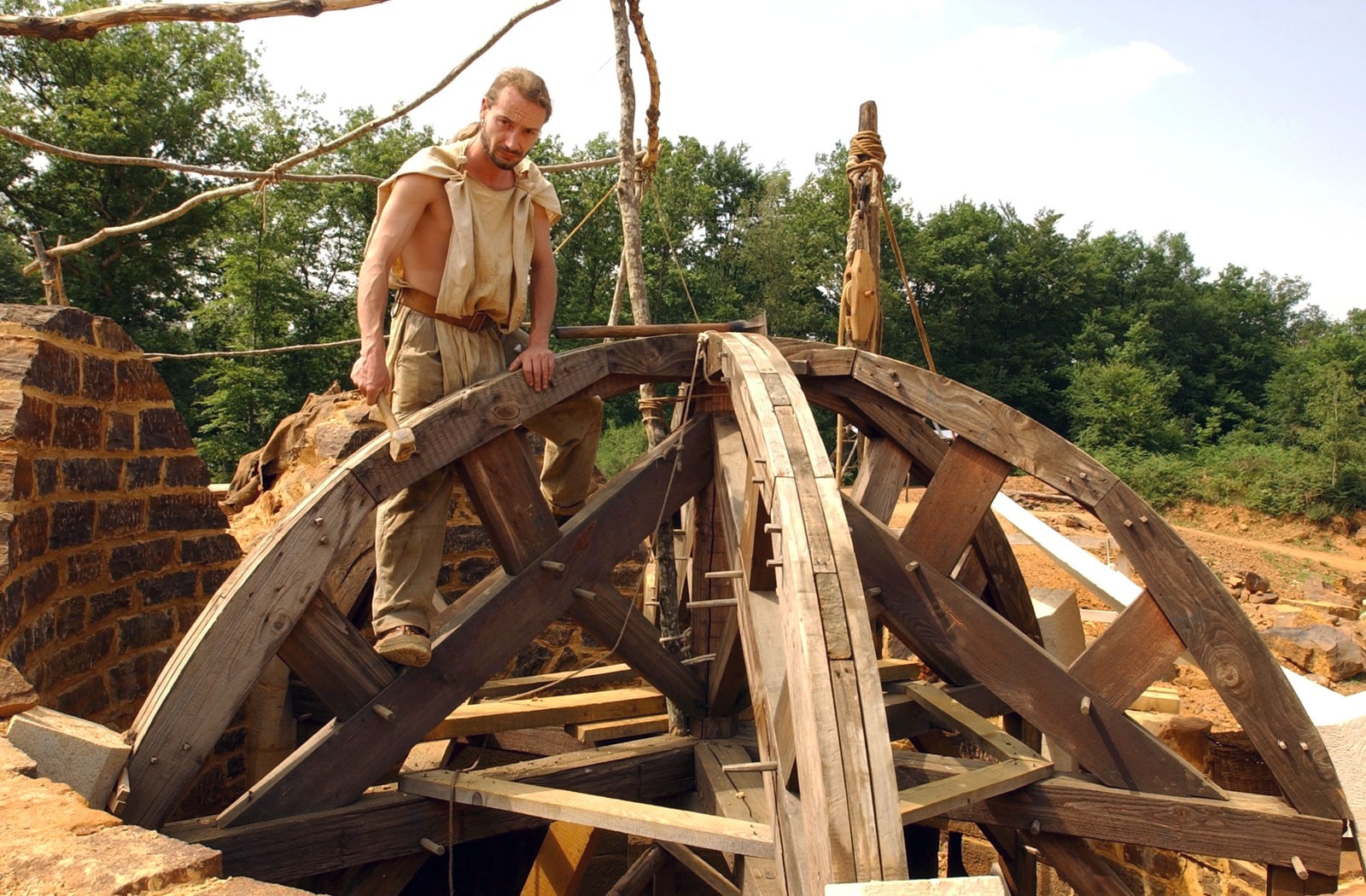 A carpenter works on support timbers for a rounded roof.