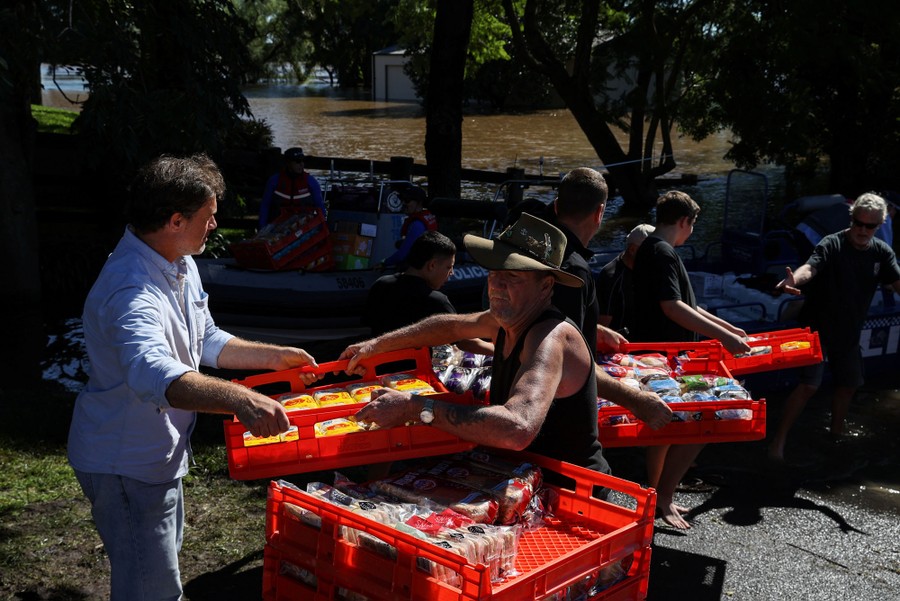 Several people carry crates of food to waiting boats.