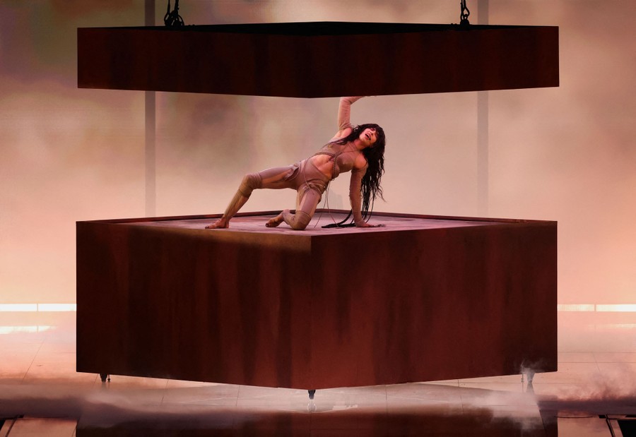 A singer performs on a cubic platform on a stage.