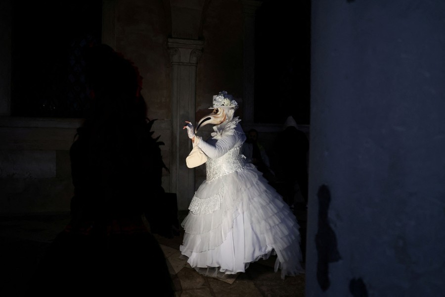Venedik'te karnaval maskesi ve kostümü giymiş bir kişi fotoğraf çektiriyor.
